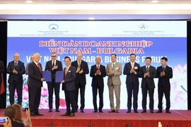 Bulgarian President Rumen Radev (sixth from the right) and other delegates witness representatives of Vietnamese and Bulgarian businesses exchanging cooperation agreements at the forum. (Photo: VNA)