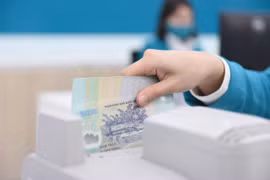 A bank teller counts money at a transaction office in Hanoi. (Photo: vietnamfinance.vn)