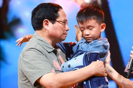 PM Pham Minh Chinh gives encouragement to a boy named Nguyen Quoc Bao, whose father and elder sister were washed away by a flood while the three were crossing a bridge in Cau Treo hamlet of Yen Thuan commune, Ham Yen district, Tuyen Quang province. (Photo: VNA)