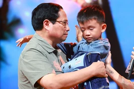 PM Pham Minh Chinh gives encouragement to a boy named Nguyen Quoc Bao, whose father and elder sister were washed away by a flood while the three were crossing a bridge in Cau Treo hamlet of Yen Thuan commune, Ham Yen district, Tuyen Quang province. (Photo: VNA)