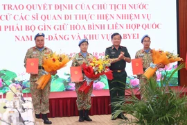 Deputy Defence Minister Senior Lieutenant General Hoang Xuan Chien (second, right) presents the State President's decisions to the three officers on October 7. (Photo: VNA)