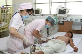 Medical staff attend to a patient suffering from dengue fever (Photo: VNA)
