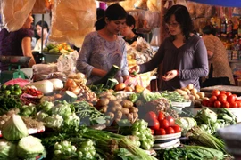 Consumers buy vegetable at a traditional market (Photo: VNA)
