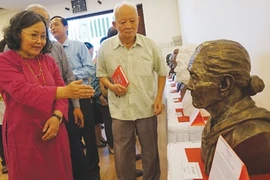 Artist Lai Thi Kim Thanh (left) describes her sculpture of Ho Thi Bi, who was awarded the title of Hero of the People's Armed Forces (Photo: VNA)