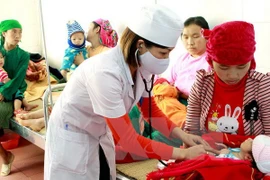 A medical worker examine a child patient (Photo: VNA)