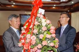 Vietnamese Ambassador to Laos Nguyen Manh Hung (L) handed over Party General Secretary Nguyen Phu Trong's greeting flowers to Lao representative Thongsavan Phomvihan. Photo: VNA