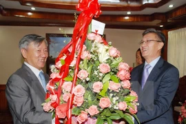 Vietnamese Ambassador to Laos Nguyen Manh Hung (L) handed over Party General Secretary Nguyen Phu Trong's greeting flowers to Lao representative Thongsavan Phomvihan. Photo: VNA