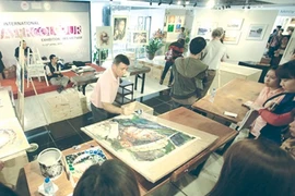 A Canadian artist paints at the first large-scale watercolour exhibition in Ha Noi. (Photo: VNA)