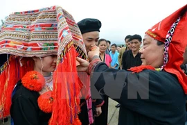 A wizard (R) offers congratulatory alcohol to the newly-wed couple of the ethnic Dao people (Photo: VNA)