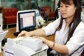 A teller counts notes at a branch of the Viet Nam International Bank (VIB) in Hanoi (Photo: VNA)