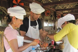 Tourists learn how to make salad during a cooking class at Water Wheel Restaurant in Tra Que herb village in Hoi An town (Source: VNA)