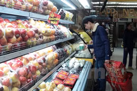 A consumer selects fruits at a supermarket (Photo: VNA)