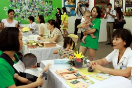 A nutrition expert (R) gives advice to a mother (Photo: VNA)