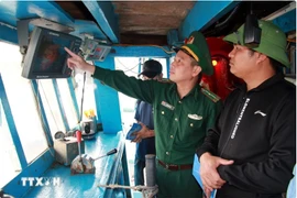 A border guard officer checks monitoring devices on a fishing vessel (Photo: VNA) 