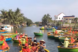 Tourists take a boat ride to explore the Bay Mau coconut forest. (Photo: VietnamPlus)