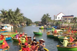 Tourists take a boat ride to explore the Bay Mau coconut forest. (Photo: VietnamPlus)