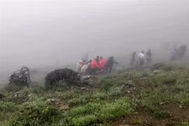 This grab taken from handout video footage released by Iranian Red Crescent Society (IRCS) on May 20, 2024 shows rescuers recovering bodies at the site of President Ebrahim Raeisi's helicopter crash in a fog-shrouded mountainous area of northwest Iran. (Photo: AFP/VNA) 