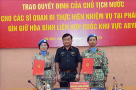 Deputy Minister of National Defence Senior Lieutenant General Hoang Xuan Chien (right) hands over the President's decision to two officers (Photo: VNA)