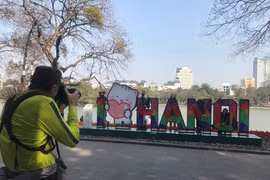 Foreign tourists take photos at Hoan Kiem Lake (Photo: daidoanket.vn)