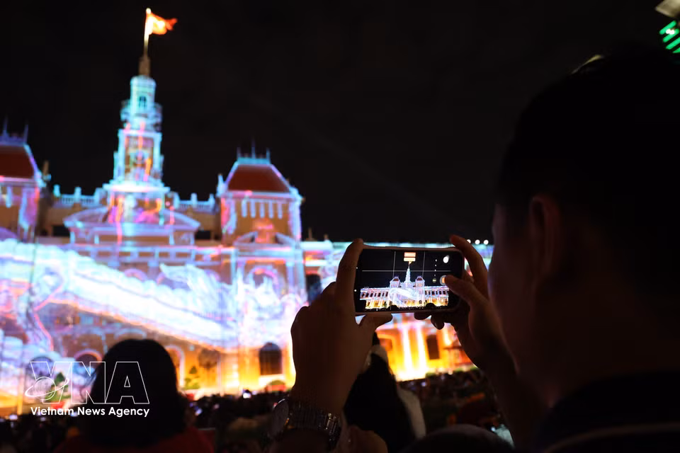 Visitors capture striking moments from the 3D mapping projections. (Photo: VNA)