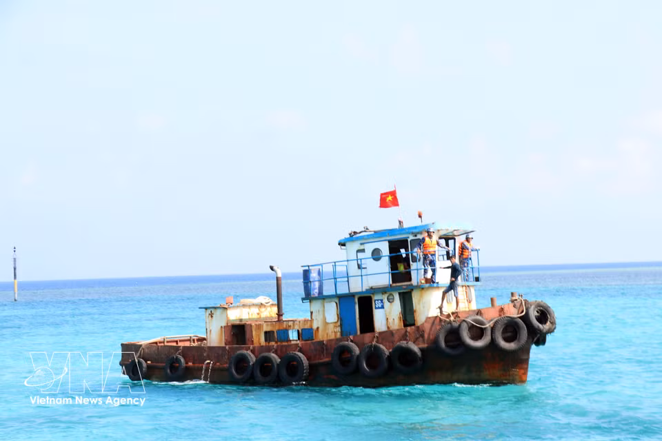 The national flag flutters on a tugboat near the pier area of Da Lon B Island. (Photo: VNA)