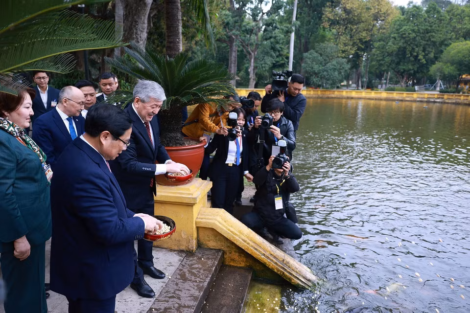 The two Prime Ministers feed fish at President Ho Chi Minh’s fish pond. (Photo: VNA)