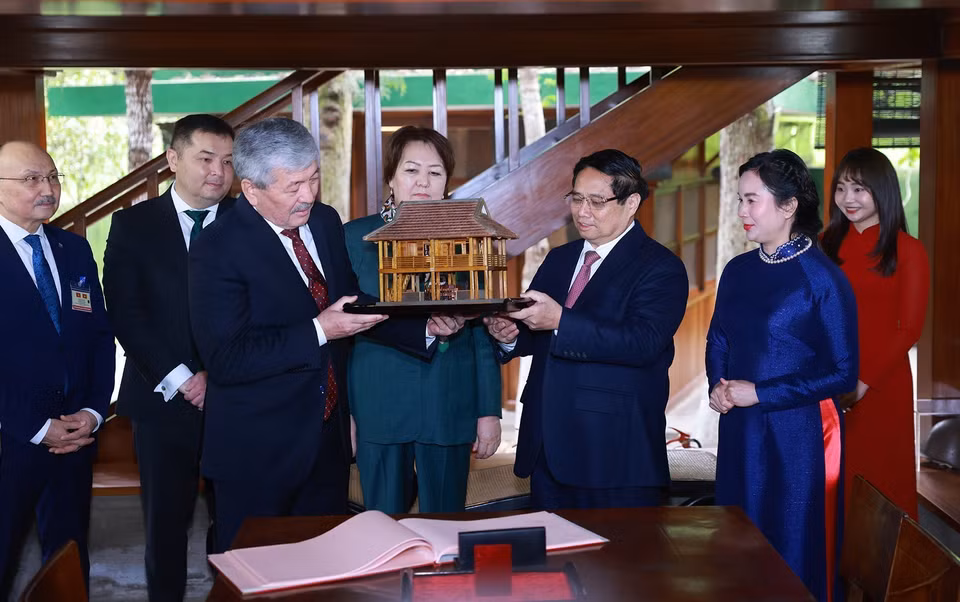 Prime Minister Pham Minh Chinh presents a model of President Ho Chi Minh’s stilt house to Prime Minister Adylbek Kasymaliev. (Photo: VNA)