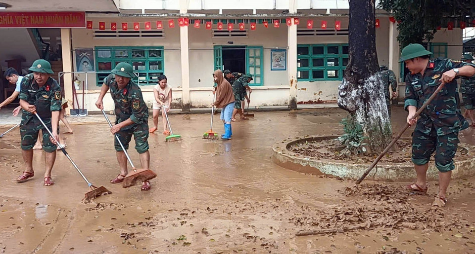 Military personnel help residents clean up and restore the environment following the floods. (Photo: VNA)