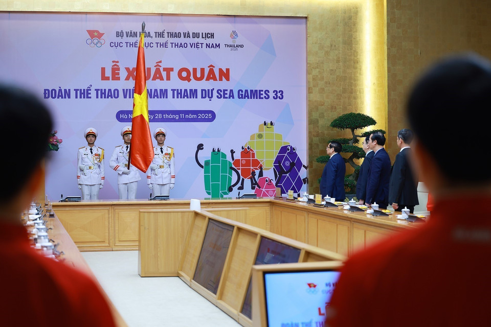 Prime Minister Pham Minh Chinh and representatives of national team athletes and coaches perform the national flag salute ceremony. (Photo: VNA)