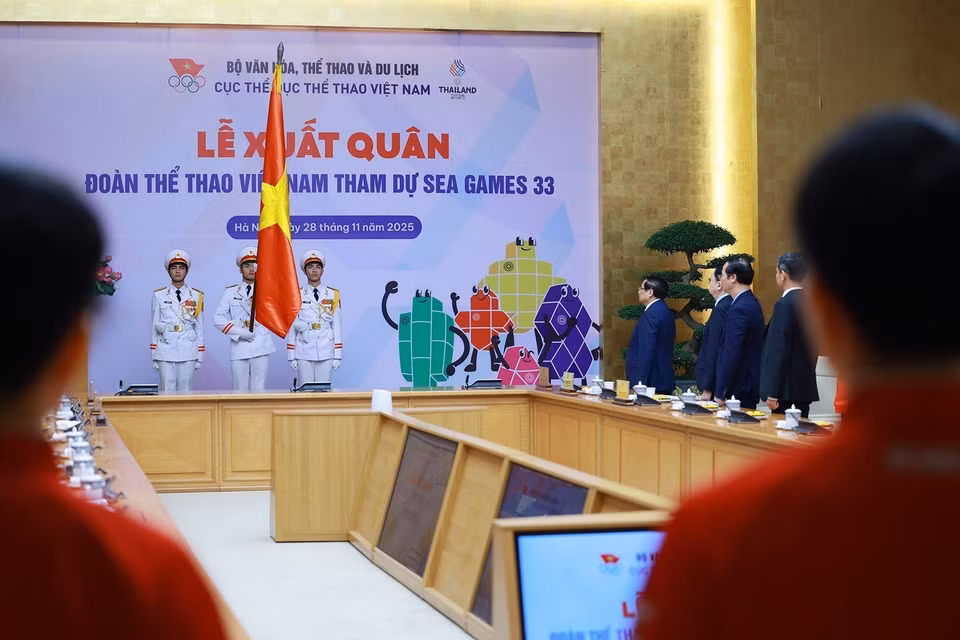 Prime Minister Pham Minh Chinh and representatives of national team athletes and coaches perform the national flag salute ceremony. (Photo: VNA)