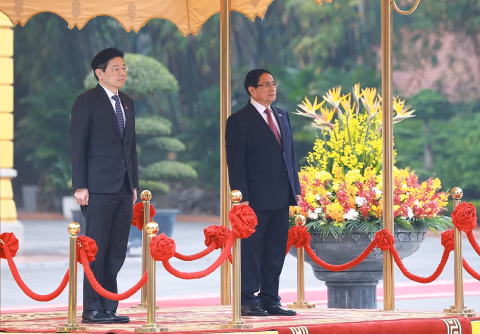 Prime Minister Pham Minh Chinh and Singaporean Prime Minister Lawrence Wong listen to the national anthems of both countries performed by the military band. (Photo: VNA)