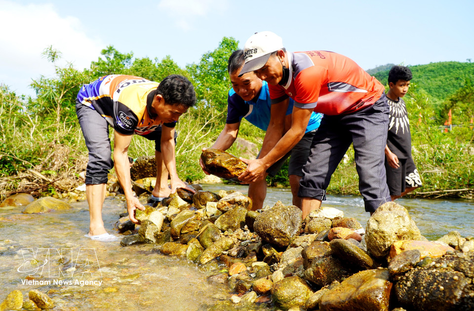 Local residents transport stones to block the water flow as part of the ritual. (Photo: VNA)