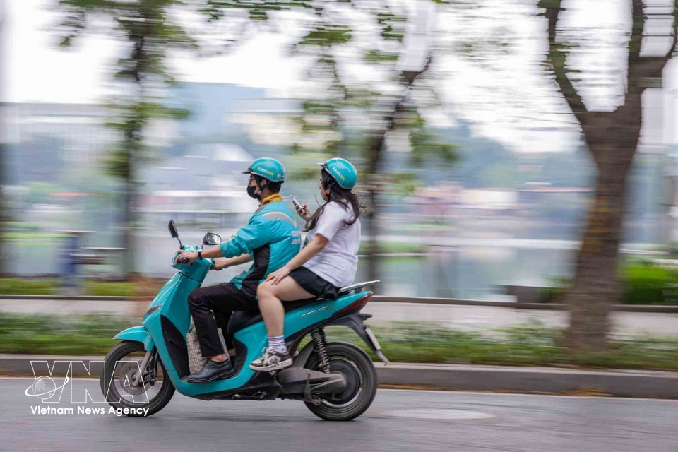 A ride-hailing driver uses an electric motorbike to carry passengers along Nguyen Du Street in Hanoi. (Photo: VNA)