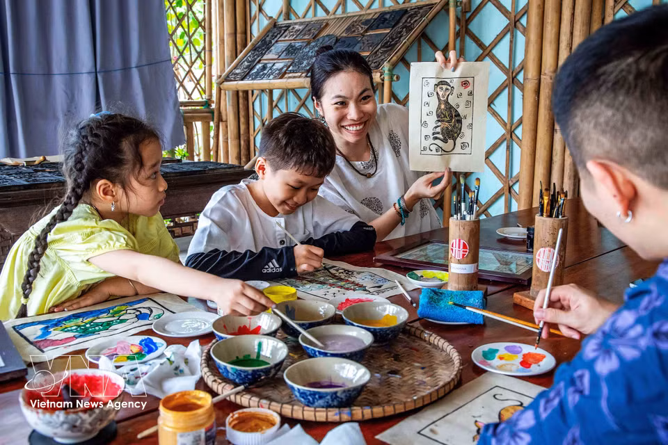Visitors are delighted after completing a Sinh village painting themselves. (Photo: VNA)