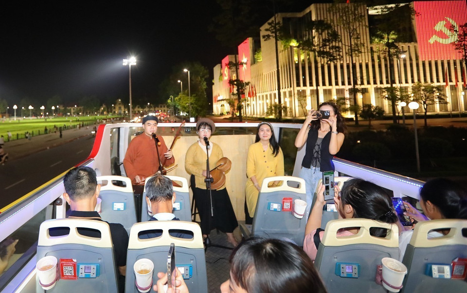 Passengers enjoy Hanoi’s illuminated landmarks while listening to live performances of traditional “xam” melodies by young artists. (Photo: VNA)