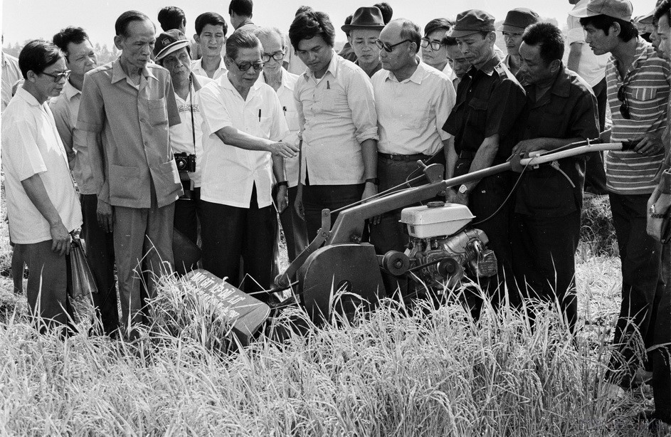 Party General Secretary Nguyen Van Linh examines a rice-cutting machine made by Phuoc Tu Cooperative (Long An, 1988). (Photo: VNA)