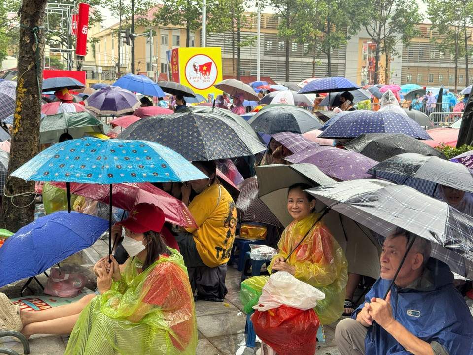 Love and pride outweigh the rain. A moment capturing Hanoians enduring the weather, patiently waiting and cheering for the armed forces. (Photo: VNA)