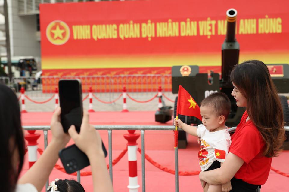 A child poses with national flags in front of the artillery battery. (Photo: VNA)