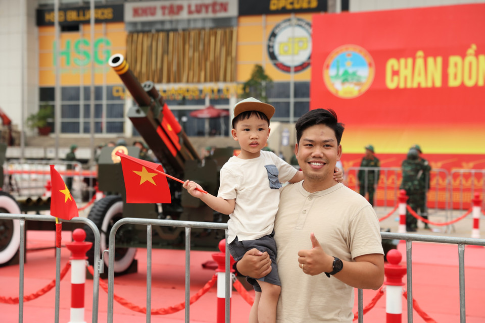 Residents pose with national flags in front of the artillery battery. (Photo: VNA)