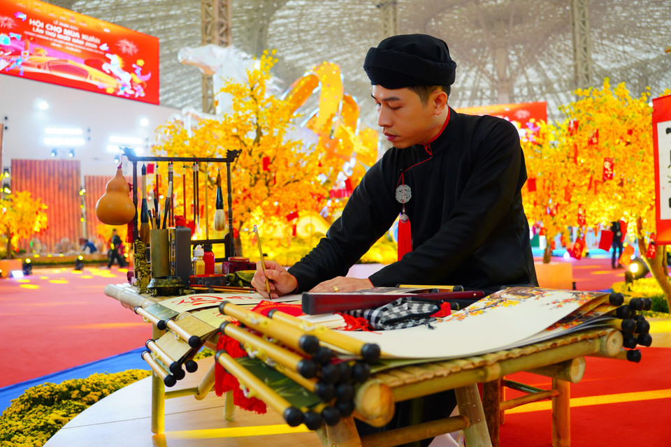 An artisan in traditional Vietnamese attire performs calligraphy. (Photo: VNA)