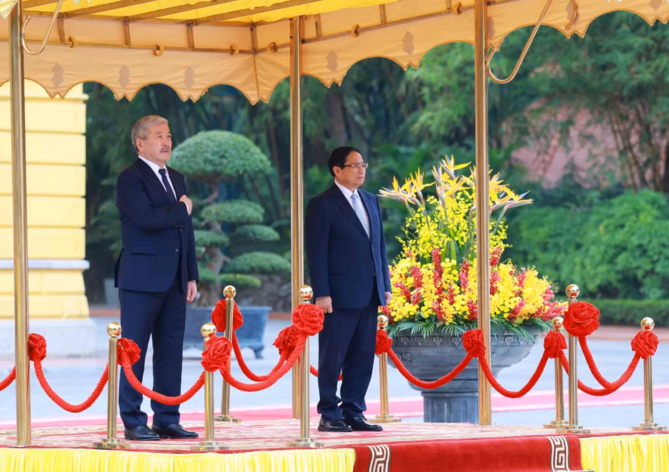 Prime Minister Pham Minh Chinh and Kyrgyz Prime Minister Adylbek Kasymaliev listen to the national anthems of both countries. (Photo: VNA)