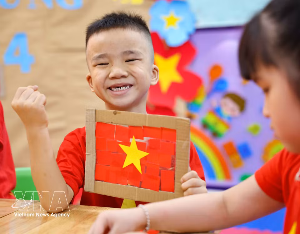 The children are delighted and proud as they complete their own national flag creations. (Photo: VNA)