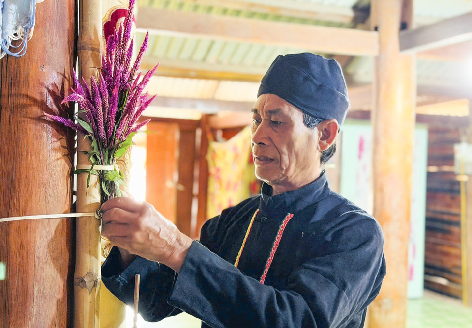 A shaman ties cockscomb flowers inside the house as part of the New Year worship ritual. (Photo: VNA)