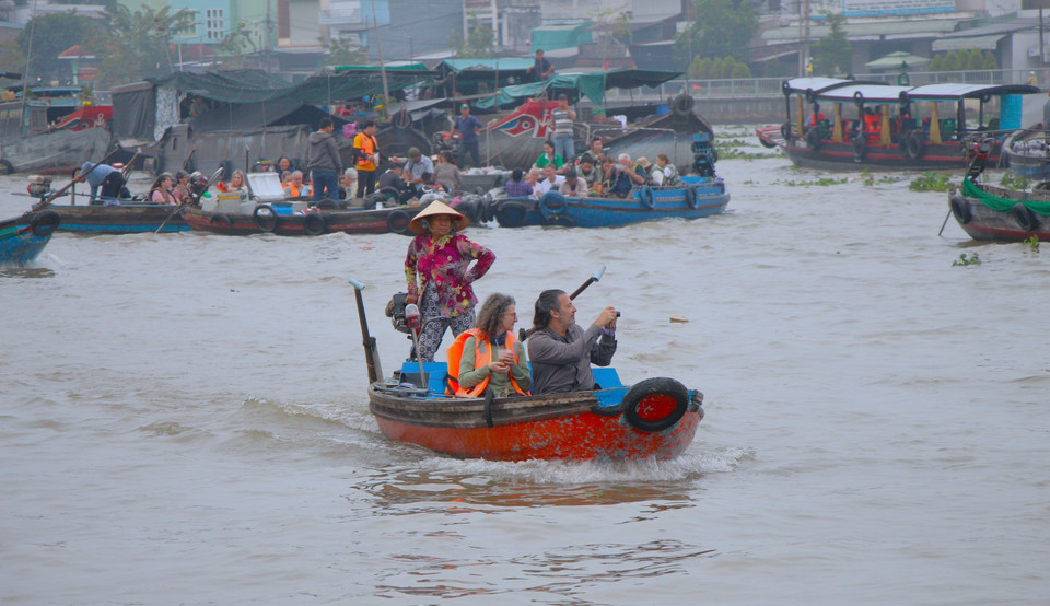 Foreign visitors explore the floating market. (Photo: VNA)