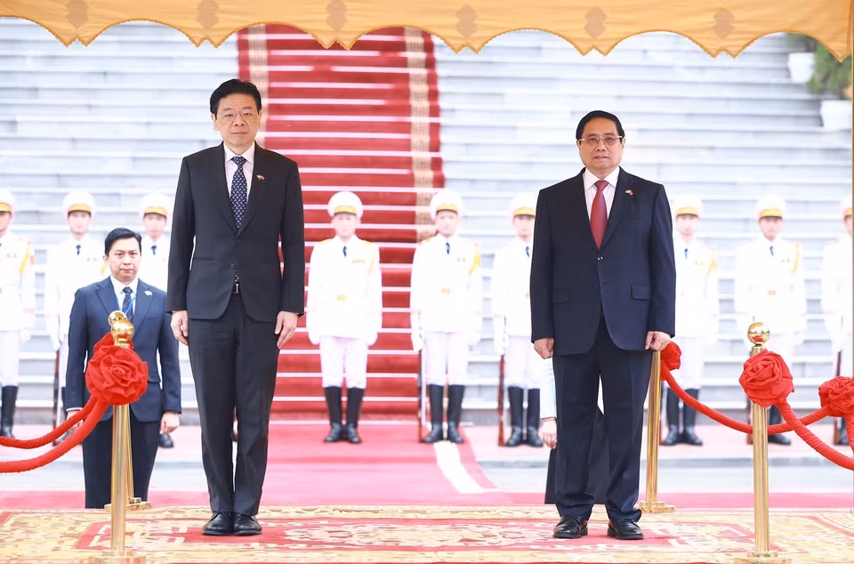 Prime Minister Pham Minh Chinh and Singaporean Prime Minister Lawrence Wong listen to the national anthems of both countries performed by the military band. (Photo: VNA)