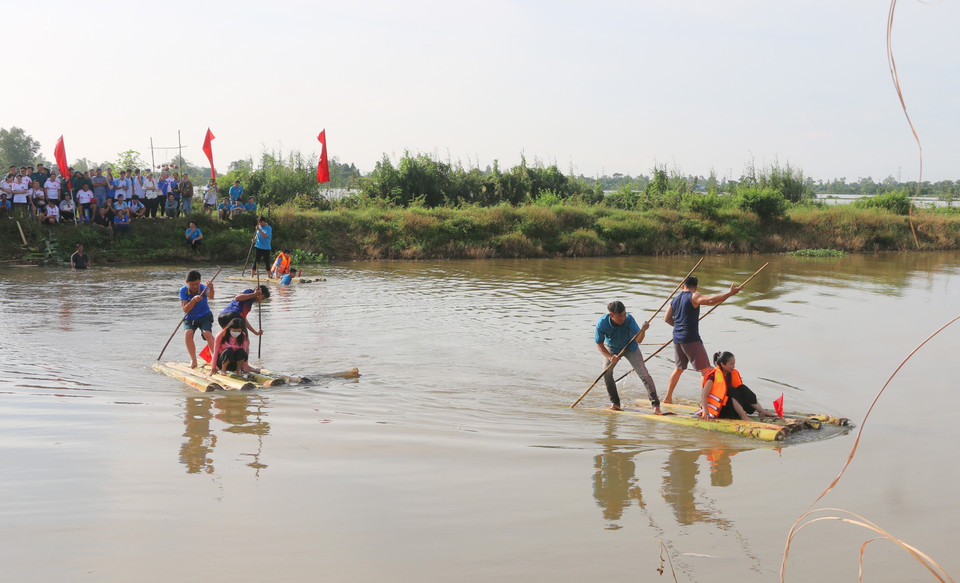 Locals and visitors join the banana-raft paddling game to ferry soldiers across the river. (Photo: VNA)