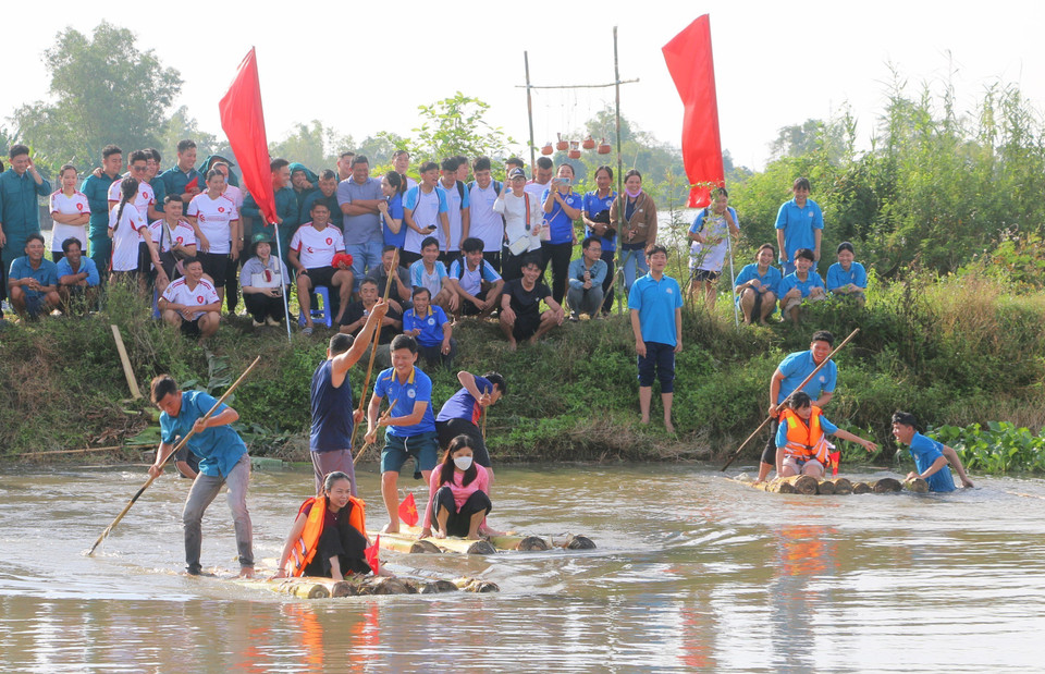 Locals and visitors join the banana-raft paddling game to ferry soldiers across the river. (Photo: VNA)