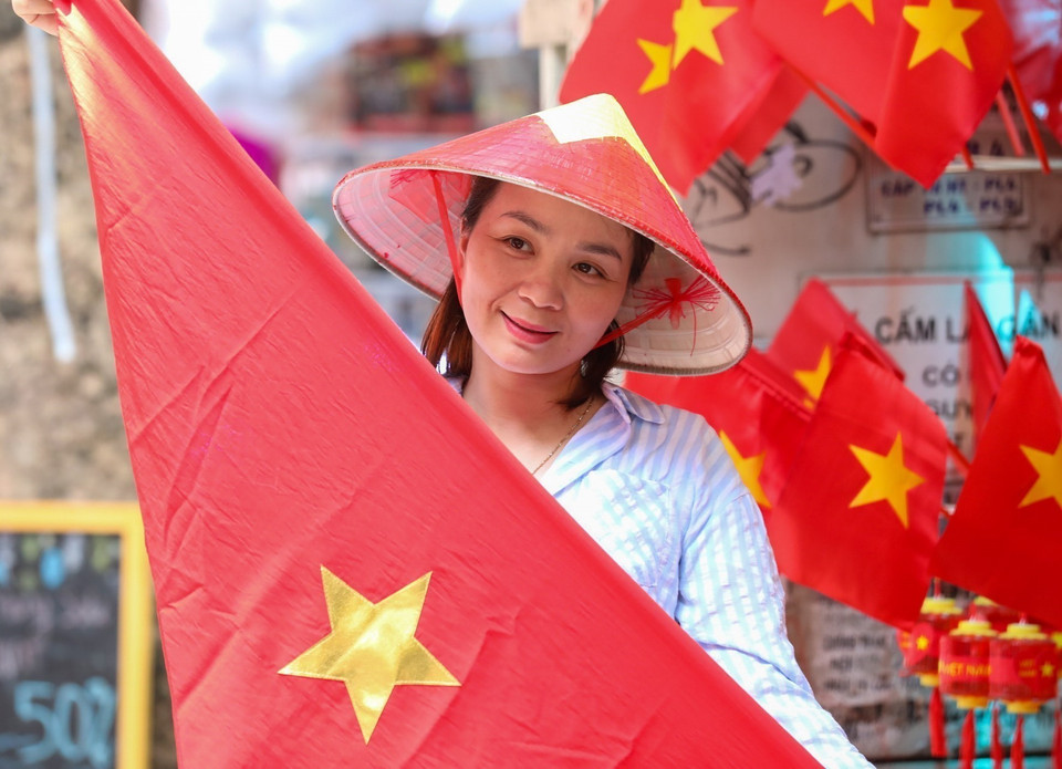 A Hanoi resident pose with national flags. (Photo: VNA)