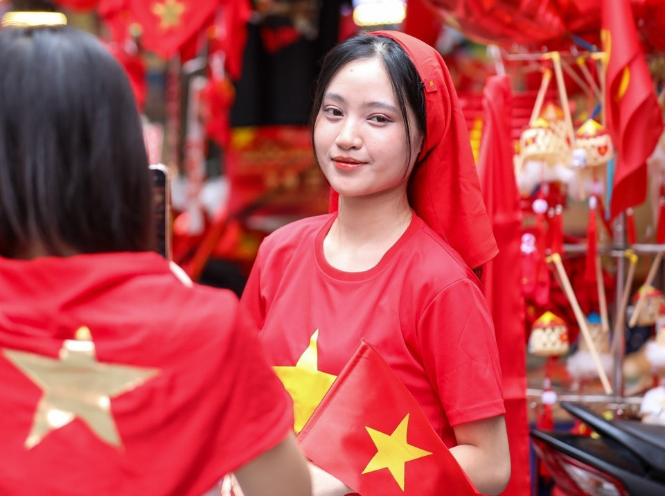 Young people pose with national flags on Hang Ma Street, Hoan Kiem District. (Photo: VNA)