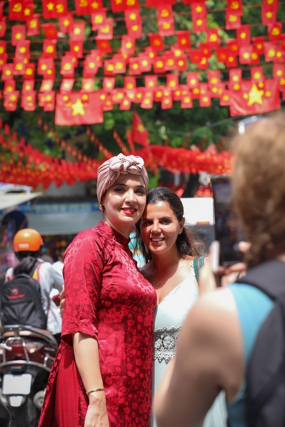 Foreign visitors enjoy taking photos in the red-filled streets of the capital. (Photo: VNA)